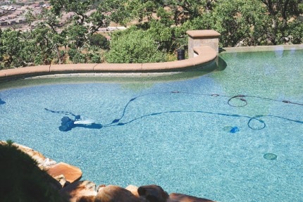 picture of a clean blue pool that was previously green and a pool vacuum cleaning the in ground swimming pool